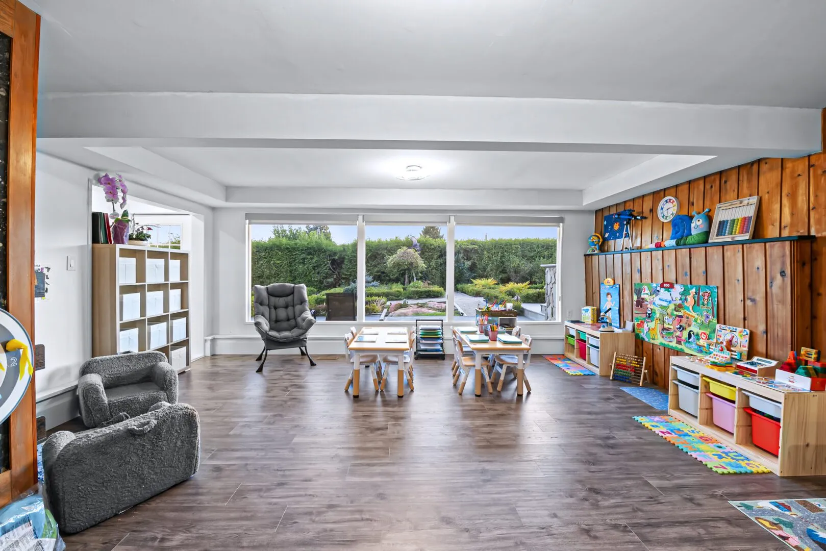 Spacious classroom with cozy reading chairs, small tables and toy shelves