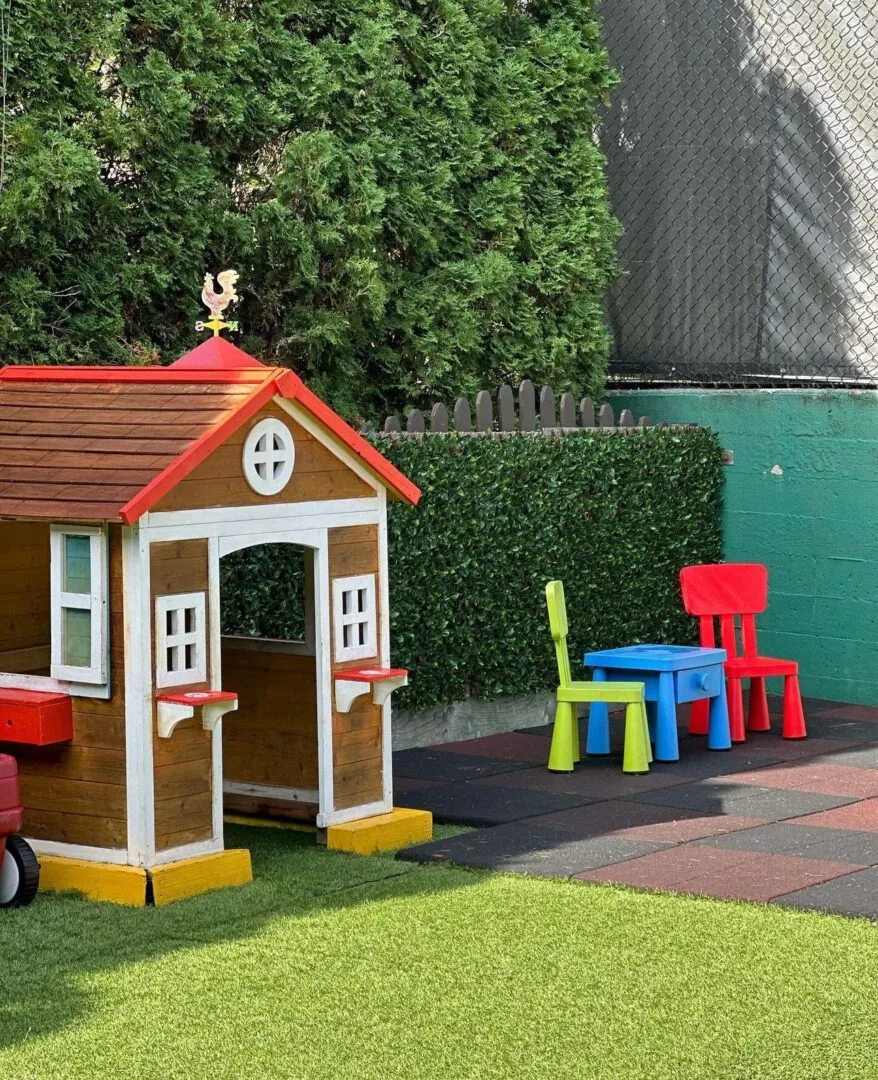 Wooden playhouse and child-sized table and chairs in the outdoor play area